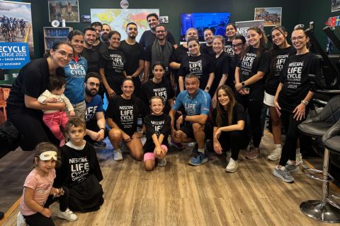 A large group of individuals in matching black t-shirts pose together for a photo, celebrating the Nescafé Life Cycle 2025 in